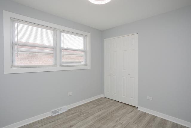 615 E 101st Pl, Chicago, IL 60628 - unfurnished bedroom with light wood finished floors, a closet, and baseboards