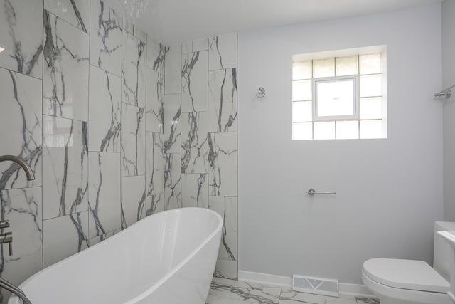 615 E 101st Pl, Chicago, IL 60628 - bathroom featuring a freestanding bath, marble finish flooring, and toilet