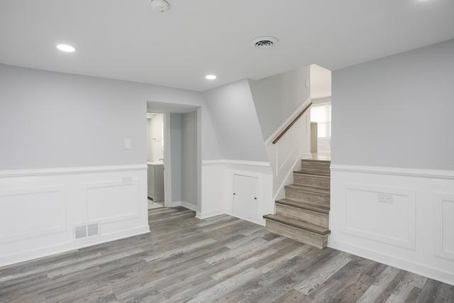 615 E 101st Pl, Chicago, IL 60628 - spare room with wood finished floors, recessed lighting, stairway, wainscoting, and a decorative wall