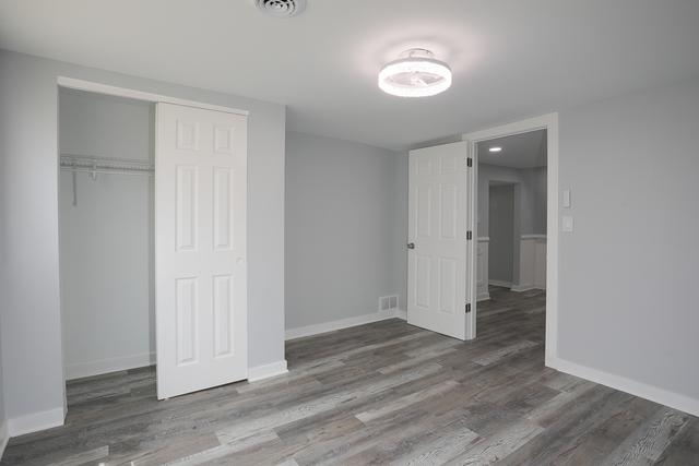 615 E 101st Pl, Chicago, IL 60628 - unfurnished bedroom featuring wood finished floors, baseboards, and a closet