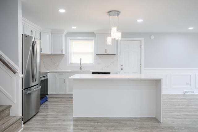 615 E 101st Pl, Chicago, IL 60628 - kitchen featuring stainless steel appliances, a sink, light countertops, a kitchen island, and wainscoting