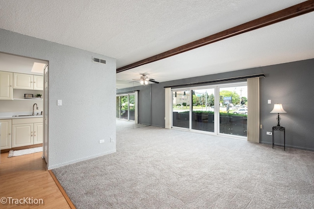 9105 S Roberts Rd Unit 1A, Hickory Hills, IL 60457 - unfurnished living room featuring a textured wall, beamed ceiling, a textured ceiling, a ceiling fan, and light carpet
