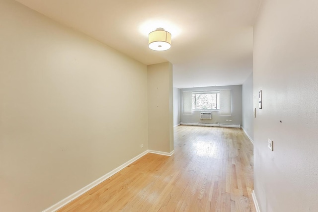 1415 W Lunt Ave Unit 203, Chicago, IL 60626 - spare room featuring baseboard heating, light wood-type flooring, baseboards, and a wall mounted air conditioner