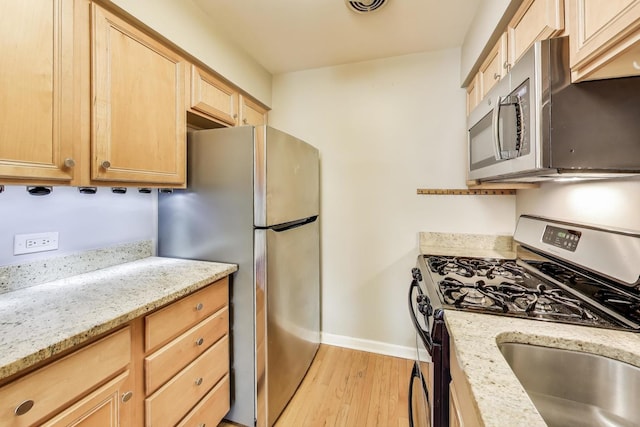 1415 W Lunt Ave Unit 203, Chicago, IL 60626 - kitchen featuring light brown cabinetry, appliances with stainless steel finishes, light wood-style flooring, light stone countertops, and baseboards