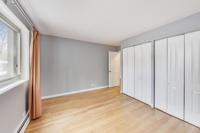 1415 W Lunt Ave Unit 203, Chicago, IL 60626 - unfurnished bedroom with two closets, a baseboard radiator, light wood-style flooring, and baseboards