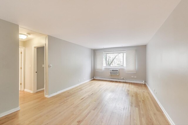 1415 W Lunt Ave Unit 203, Chicago, IL 60626 - unfurnished room with a baseboard radiator, light wood finished floors, baseboards, and a wall mounted AC