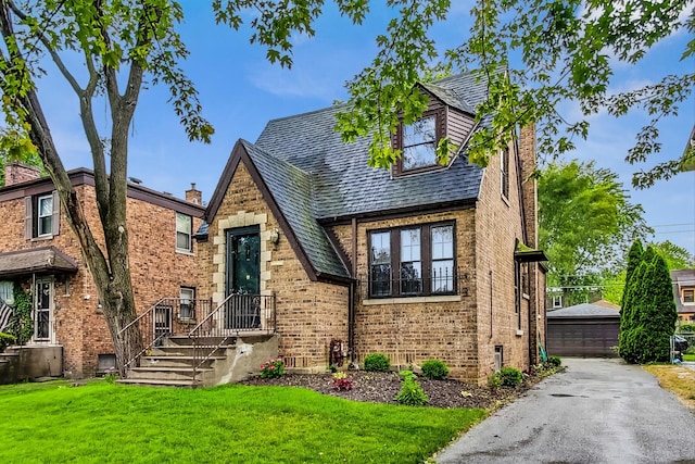 10752 S Washtenaw Ave, Chicago, IL 60655 - tudor house featuring a front yard, brick siding, an outbuilding, and a garage