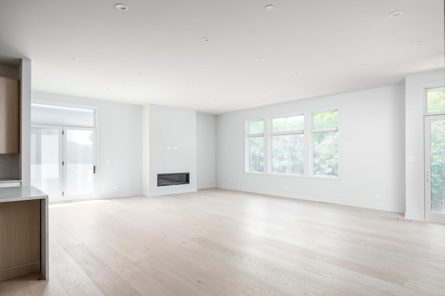 8 Heritage Dr, Highland Park, IL 60035 - unfurnished living room featuring light wood-style flooring, a glass covered fireplace, and baseboards