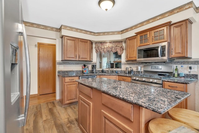 1072 Ronald Dr, Joliet, IL 60435 - kitchen with appliances with stainless steel finishes, light wood finished floors, tasteful backsplash, a sink, and glass insert cabinets