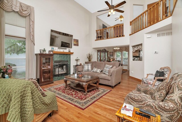 1072 Ronald Dr, Joliet, IL 60435 - living room with ceiling fan, wood finished floors, a tiled fireplace, baseboards, and high vaulted ceiling