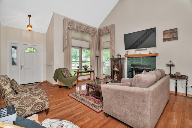 1072 Ronald Dr, Joliet, IL 60435 - living room with high vaulted ceiling, wood finished floors, a tiled fireplace, and baseboards