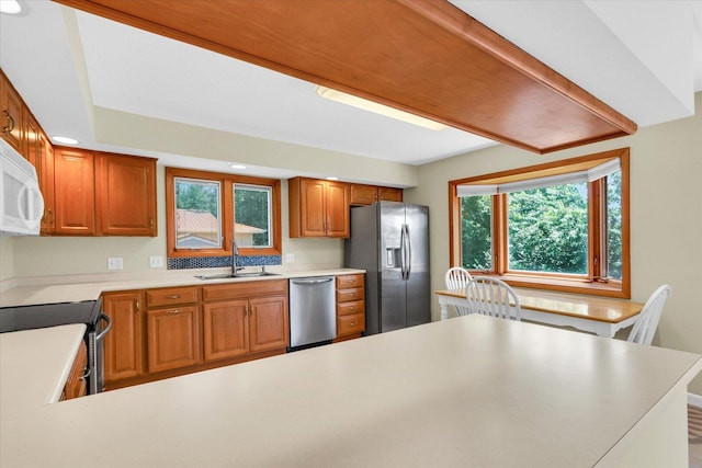 309 E Mchenry St, Urbana, IL 61801 - kitchen featuring appliances with stainless steel finishes, light countertops, brown cabinets, and a peninsula