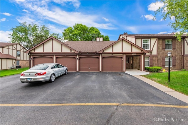 2800 Northampton Dr Unit A2, Rolling Meadows, IL 60008 - tudor home with asphalt driveway, an attached garage, a front lawn, and stucco siding
