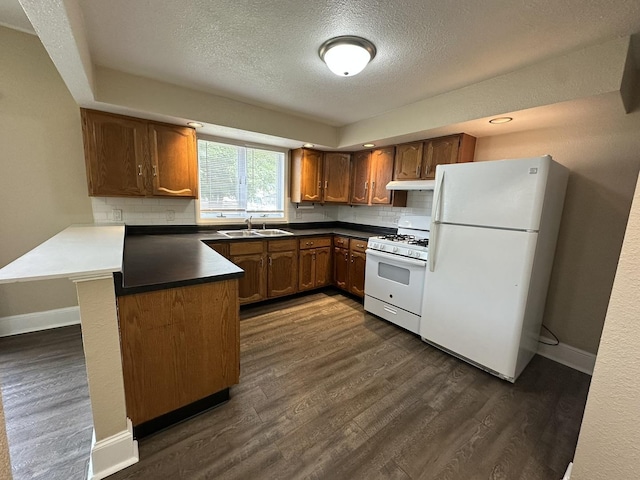 1109 S Locust Ave, Freeport, IL 61032 - kitchen with white appliances, under cabinet range hood, a peninsula, dark wood-type flooring, and a textured ceiling