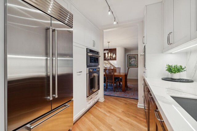 505 N Lake Shore Dr Unit 2206-2207, Chicago, IL 60611 - kitchen with stainless steel appliances, a chandelier, light wood-type flooring, white cabinetry, and light stone countertops