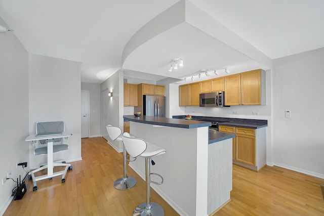 1640 Maple Ave Unit 1105, Evanston, IL 60201 - kitchen with appliances with stainless steel finishes, dark countertops, a kitchen breakfast bar, and light wood-style floors