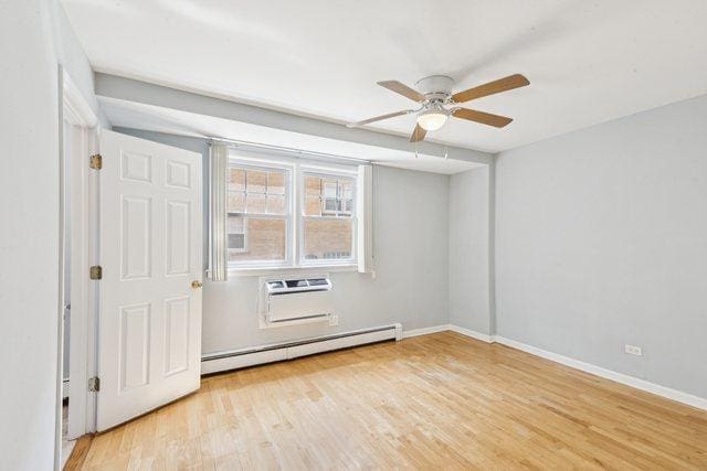 1819 W Touhy Ave Unit 2, Chicago, IL 60626 - spare room with a baseboard radiator, ceiling fan, wood finished floors, and baseboards