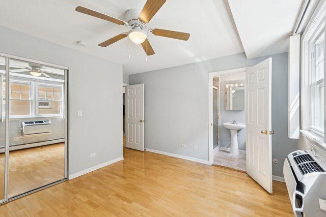 1819 W Touhy Ave Unit 2, Chicago, IL 60626 - unfurnished bedroom with multiple windows, light wood finished floors, baseboards, and a baseboard radiator