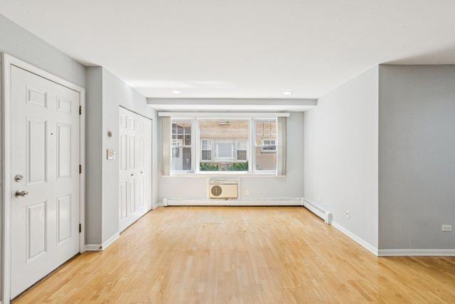 1819 W Touhy Ave Unit 2, Chicago, IL 60626 - spare room with light wood-style floors, baseboards, and a wall mounted AC