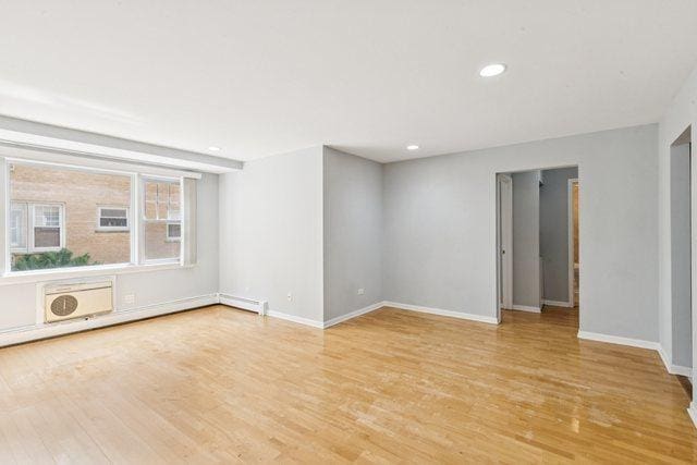 1819 W Touhy Ave Unit 2, Chicago, IL 60626 - spare room with light wood-style floors, baseboards, recessed lighting, and an AC wall unit