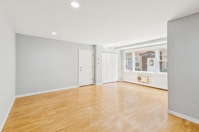 1819 W Touhy Ave Unit 2, Chicago, IL 60626 - empty room featuring baseboards, light wood finished floors, recessed lighting, and a wall unit AC