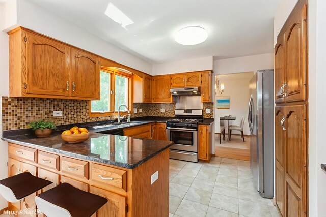 8885 Dryden St, Woodridge, IL 60517 - kitchen featuring appliances with stainless steel finishes, a peninsula, under cabinet range hood, and brown cabinets