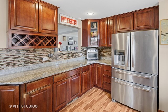 6967 W Wolfram St, Chicago, IL 60634 - kitchen with stainless steel refrigerator with ice dispenser, light stone counters, light wood-style floors, glass insert cabinets, and decorative backsplash