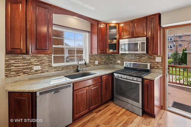 6967 W Wolfram St, Chicago, IL 60634 - kitchen with appliances with stainless steel finishes, light wood finished floors, backsplash, and glass insert cabinets