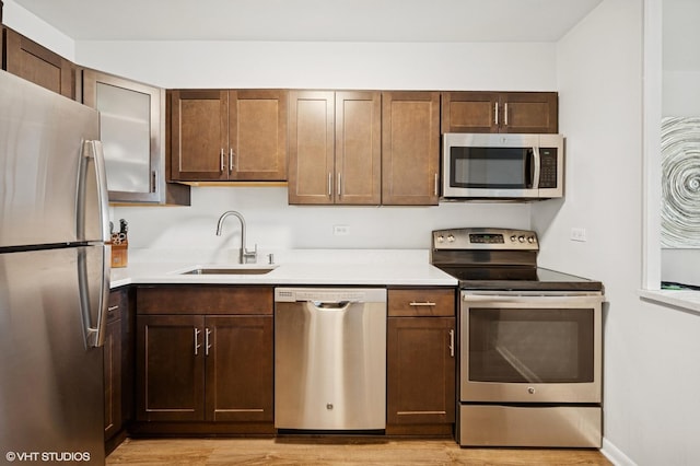 1560 N Sandburg Ter Unit 1605J, Chicago, IL 60610 - kitchen with stainless steel appliances, a sink, light wood-style flooring, and light countertops