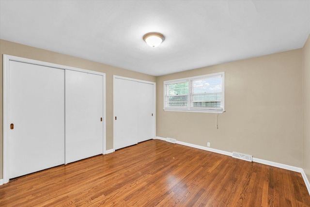 1204 Mayfair Rd, Champaign, IL 61821 - unfurnished bedroom featuring multiple closets and wood finished floors