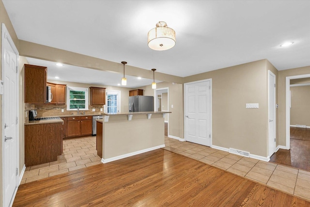 1204 Mayfair Rd, Champaign, IL 61821 - kitchen with appliances with stainless steel finishes, light wood-type flooring, a kitchen bar, light countertops, and a kitchen island