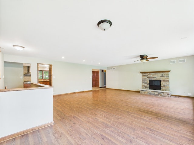 2208 Fiesta Dr, Joliet, IL 60432 - unfurnished living room with a ceiling fan, light wood-style flooring, a stone fireplace, baseboards, and recessed lighting
