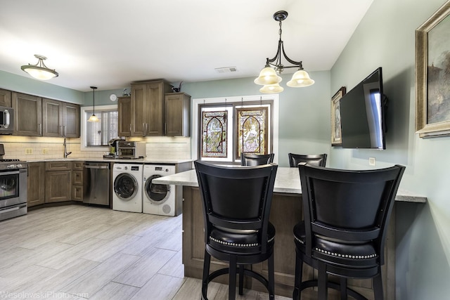 4876 N Hermitage Ave Unit 104, Chicago, IL 60640 - kitchen with stainless steel appliances, a sink, light countertops, tasteful backsplash, and a breakfast bar