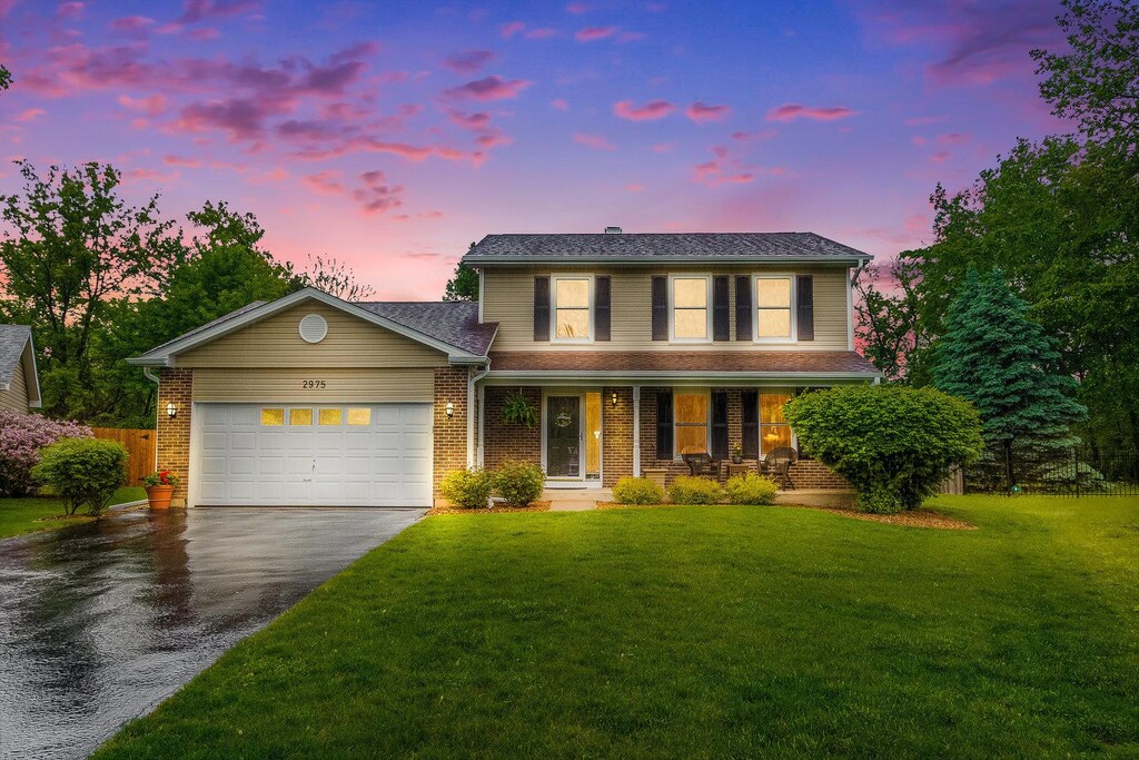 2975 Partridge Ct, Aurora, IL 60502 - traditional home with asphalt driveway, a porch, a garage, a front yard, and brick siding