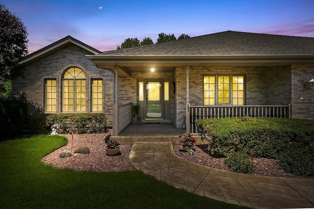 22314 Jeanette Ct, Frankfort, IL 60423 - exterior entry at dusk with a porch, brick siding, and a shingled roof