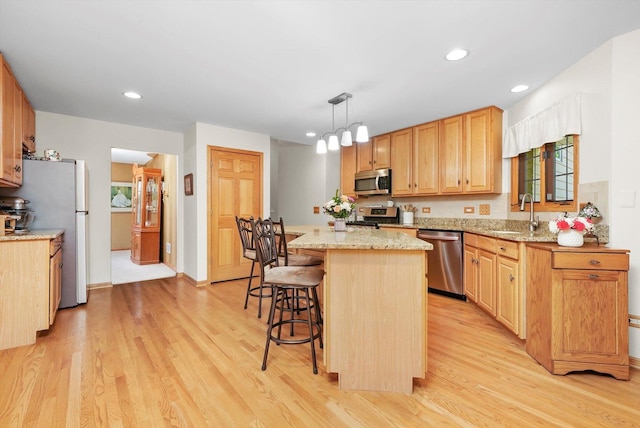 22314 Jeanette Ct, Frankfort, IL 60423 - kitchen with appliances with stainless steel finishes, a sink, light wood-type flooring, a breakfast bar, and recessed lighting