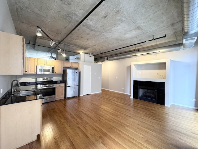 933 W Van Buren St Unit 424, Chicago, IL 60607 - kitchen featuring stainless steel appliances, dark countertops, wood finished floors, light brown cabinets, and a tile fireplace