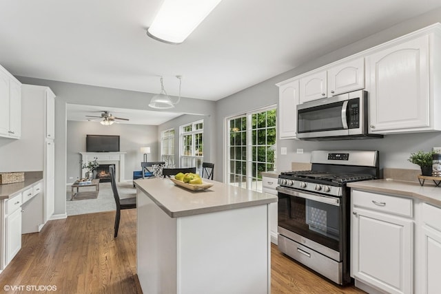 2136 Colonial St, Aurora, IL 60503 - kitchen featuring stainless steel appliances, ceiling fan, white cabinetry, and a lit fireplace