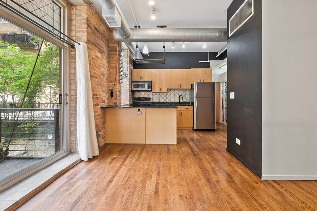 420 S Clinton St Unit 102A, Chicago, IL 60607 - kitchen featuring appliances with stainless steel finishes, light brown cabinetry, dark countertops, light wood-style flooring, and a peninsula