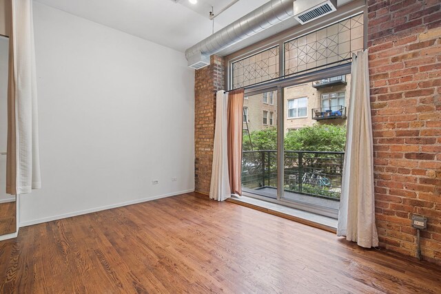 420 S Clinton St Unit 102A, Chicago, IL 60607 - unfurnished room featuring brick wall, wood finished floors, and baseboards
