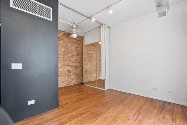420 S Clinton St Unit 102A, Chicago, IL 60607 - empty room with brick wall, light wood finished floors, rail lighting, and baseboards