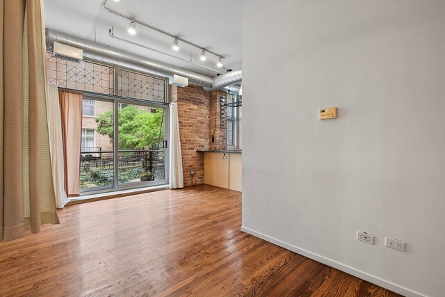 420 S Clinton St Unit 102A, Chicago, IL 60607 - empty room featuring wood finished floors, rail lighting, baseboards, and brick wall