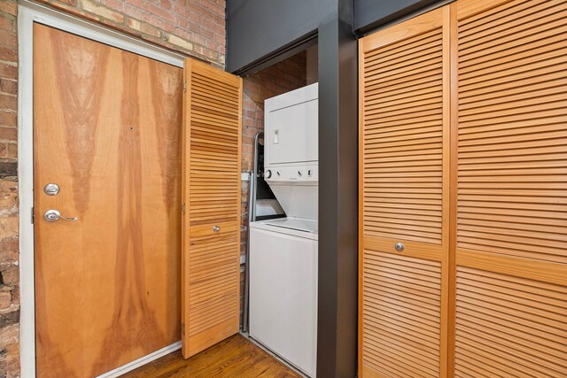 420 S Clinton St Unit 102A, Chicago, IL 60607 - laundry room with stacked washing machine and dryer, wood finished floors, and brick wall