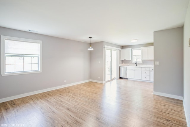 unfurnished living room with baseboards, light wood finished floors, and a sink