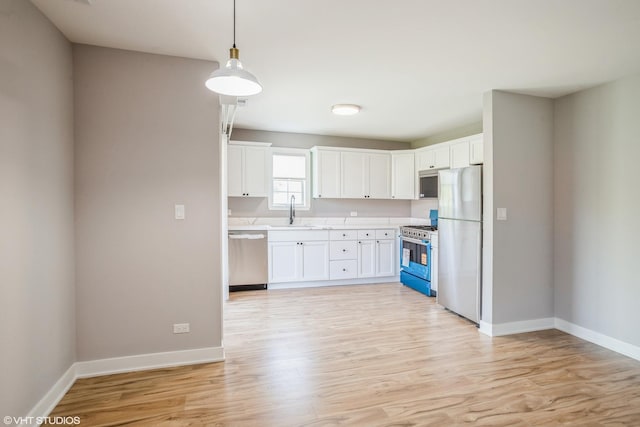 kitchen featuring appliances with stainless steel finishes, a sink, light countertops, and light wood-type flooring