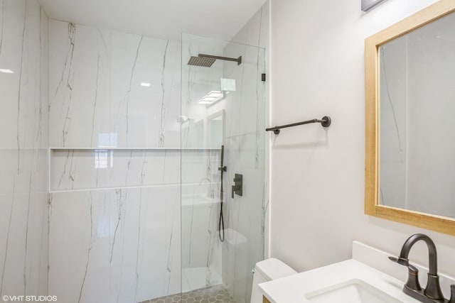full bath featuring toilet, vanity, and a marble finish shower