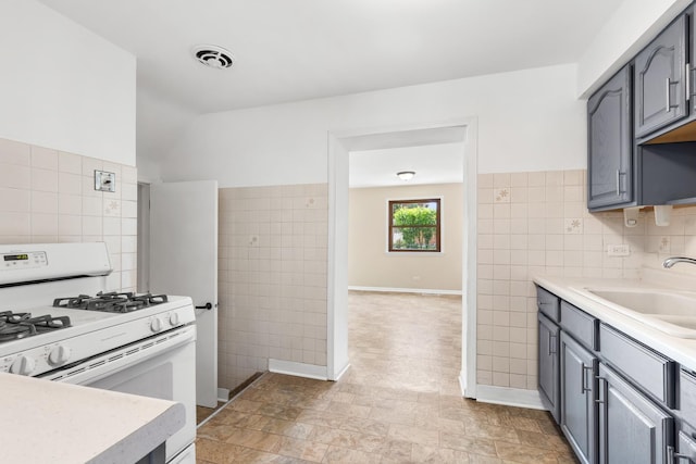 5471 N Octavia Ave, Chicago, IL 60656 - kitchen with white gas range, tile walls, gray cabinets, a sink, and light countertops