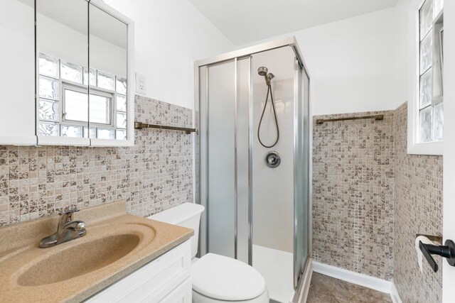 5471 N Octavia Ave, Chicago, IL 60656 - full bathroom featuring tile walls, toilet, a shower stall, vanity, and a wainscoted wall