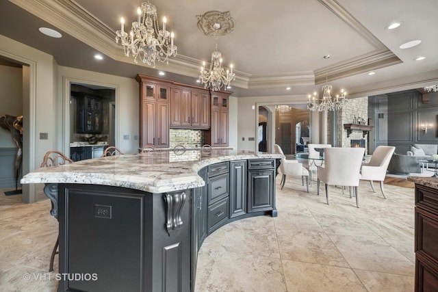 14 Vandenbergh Dr, South Barrington, IL 60010 - kitchen with a chandelier, a tray ceiling, crown molding, a kitchen bar, and light stone counters