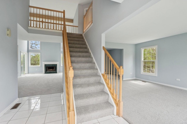 1173 Lamb Ln, Gurnee, IL 60031 - stairway featuring carpet floors, baseboards, a fireplace, tile patterned flooring, and a high ceiling